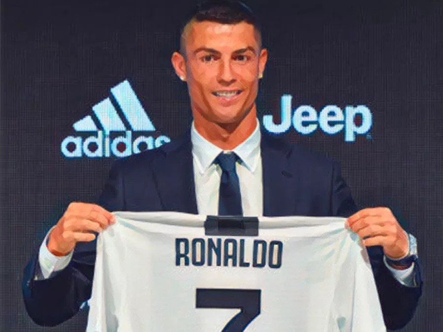 Cristiano Ronaldo sorridente mentre tiene la maglia numero 7 della Juventus durante la sua presentazione ufficiale a Torino nel luglio 2018