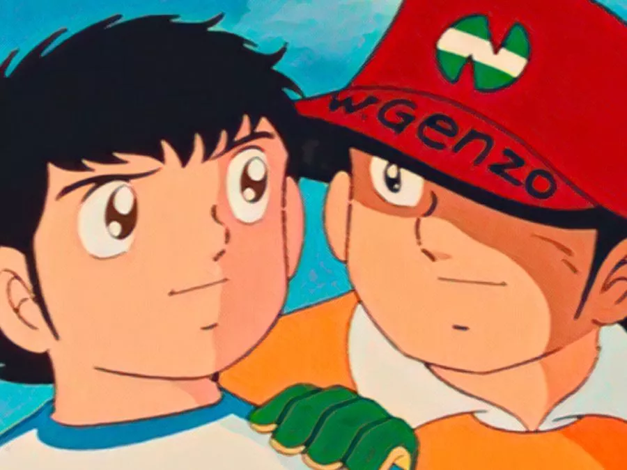 I due protagonisti dell'anime, l'attaccante Oliver Hutton con il pallone sotto il braccio e il portiere Benjamin Price con il suo iconico cappellino rosso, mentre sorridono sul campo da calcio
