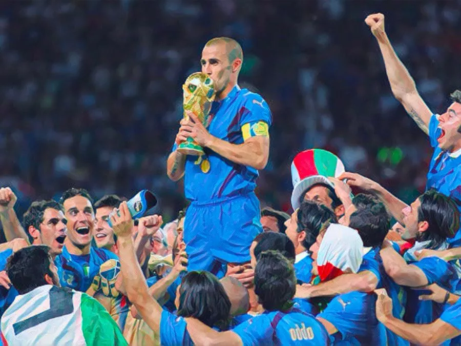 Il capitano Fabio Cannavaro alza al cielo la Coppa del Mondo del 2006 circondato dai compagni di squadra azzurri festanti sul podio di Berlino il 9 luglio 2006